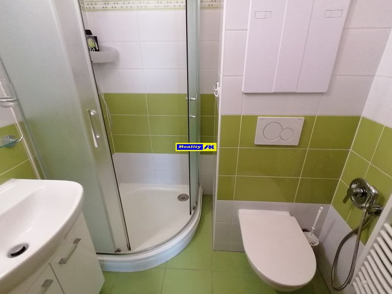 Badezimmer mit Dusche und grünen Fliesen in einer 2-Zimmer-Wohnung.
