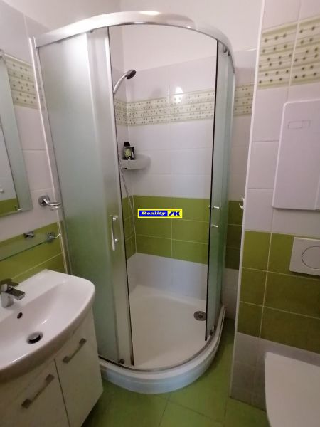 Badezimmer mit Dusche und grünen Fliesen in einer 2-Zimmer-Wohnung.