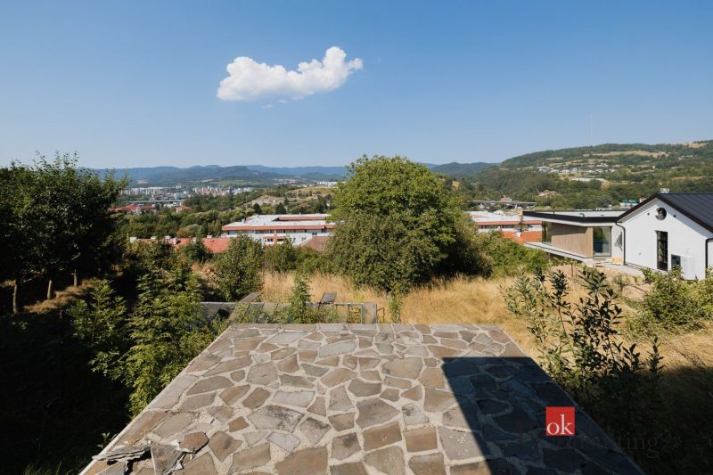 Blick auf einen Teil von Banská Bystrica von der Komenského Straße, umgeben von Einfamilienhäusern und Natur.