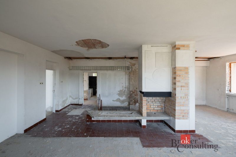 Ein Einfamilienhaus mit Kamin, unverputzte Wände und Fliesen im Innenraum.