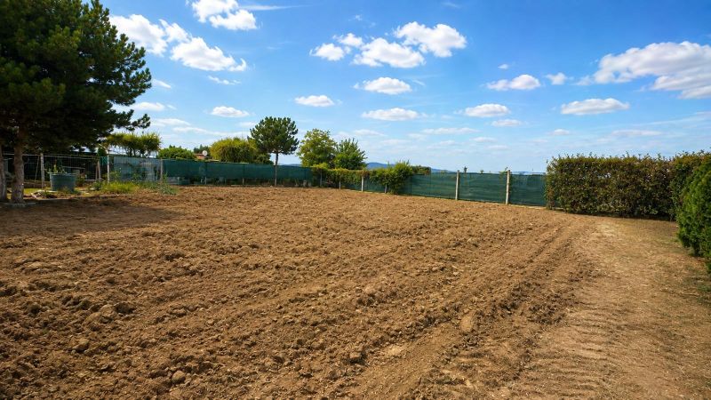 Baugrundstücke in Pravotice mit bewirtschaftetem Boden, grüner Hecke und blauem Himmel.