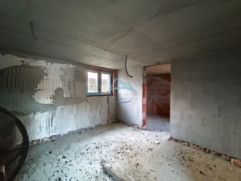 Unvollendeter Innenraum eines Einfamilienhauses mit unverputzten Wänden und Betonboden.