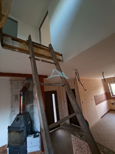 Innenrenovierung in einem Einfamilienhaus, dominiert von Treppen und einem Holzofen.