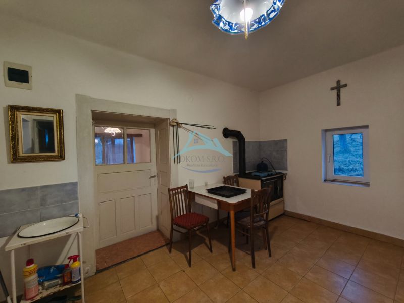 Küche in einem Einfamilienhaus mit einem Ofen, einem einfachen Tisch und einem Stuhl.
