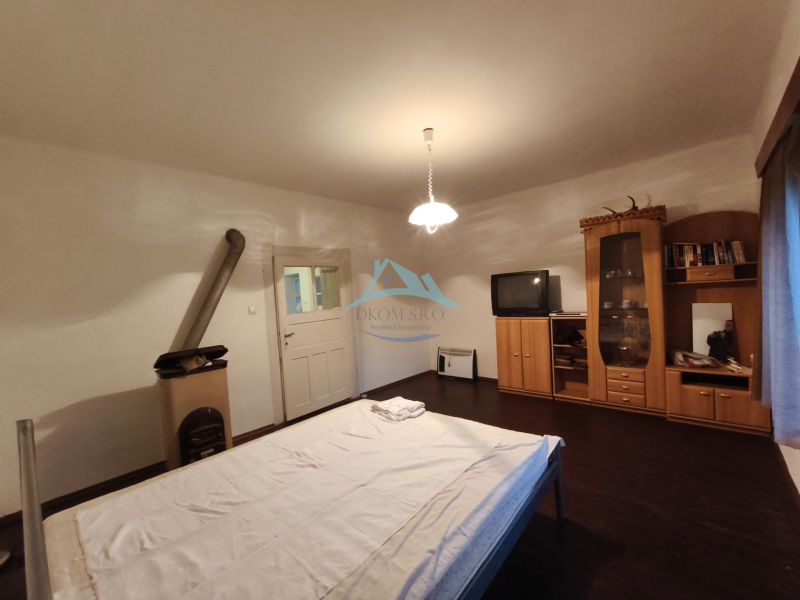 Schlafzimmer in einem Einfamilienhaus mit dunklem Boden, Möbeln, Fernseher und Ofen.