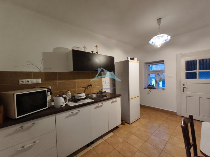 Küche in einem Einfamilienhaus mit braunen Fliesen, ausgestattet mit Mikrowelle und Kühlschrank.
