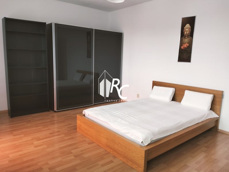 Schlafzimmer in einer 2-Zimmer-Wohnung mit Bett und großem Kleiderschrank, Boden mit Holzdekor.