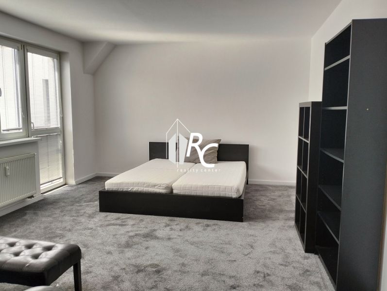 Schlafzimmer in einer 2-Zimmer-Wohnung mit Bett, Regalen und Teppich in neutralen Farben.