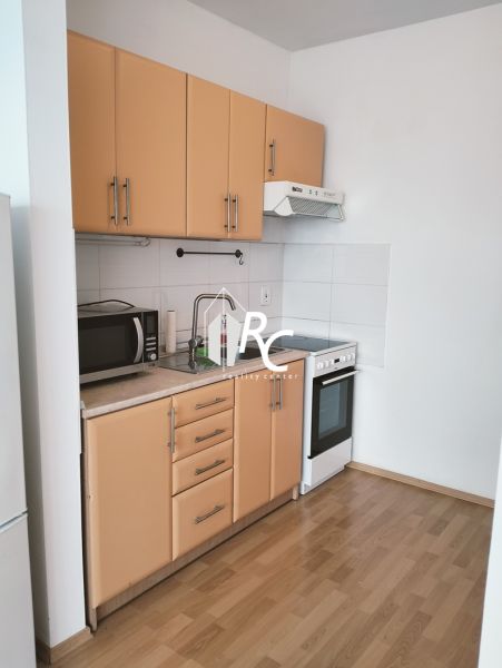 Küche in einer 2-Zimmer-Wohnung mit Holzboden, Mikrowelle und Herd.