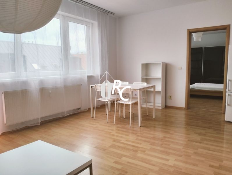 2-Zimmer-Wohnung mit Holzbodenoptik, weißem Tisch und durchsichtigen Vorhängen.