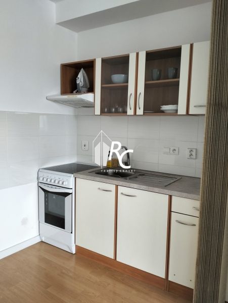 Küche mit weißen Schränken in einer 2-Zimmer-Wohnung, Boden mit Holzdekor.