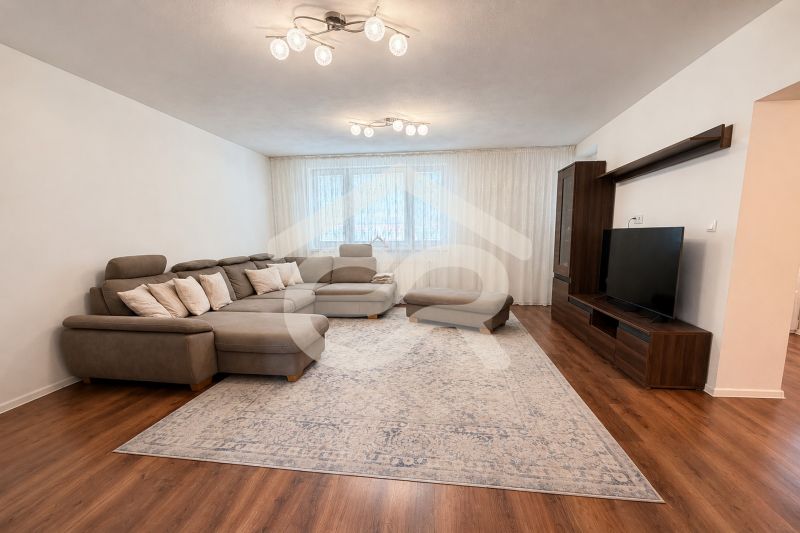 Wohnzimmer mit großem Sofa, Fernseher und Holzboden in einem Einfamilienhaus.