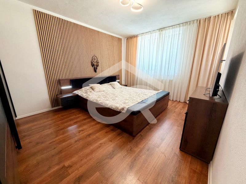 Schlafzimmer in einem Einfamilienhaus mit Bett, Vorhängen und Boden mit Holzdekor.