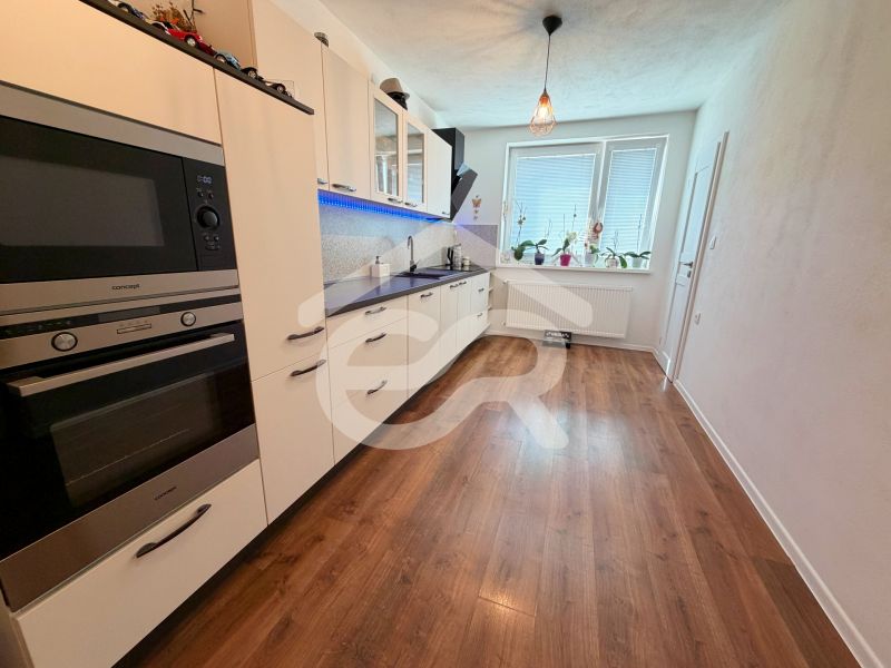 Küche in einem Einfamilienhaus mit weißer Küchenzeile und Boden in Holzoptik.