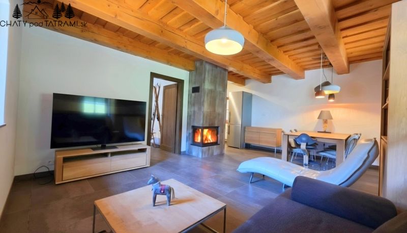 Wohnzimmer in einer Hütte mit Kamin, Fernseher und Holzbalkendecken.