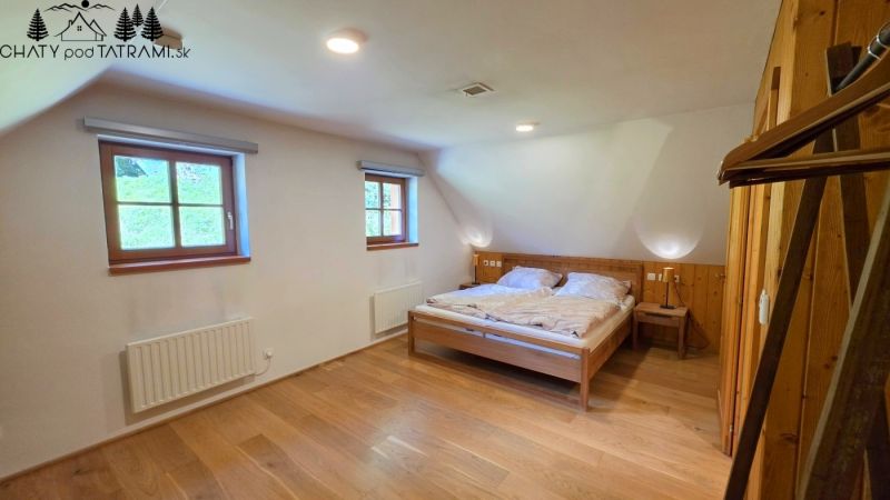 Ein Zimmer in einer Hütte mit Holzboden und einem Doppelbett.