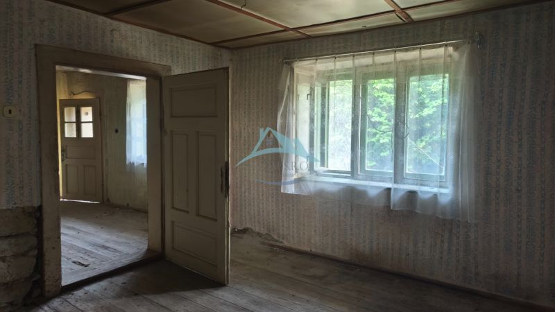 Ein altes Interieur in einem Einfamilienhaus mit Holzboden und Vorhängen an den Fenstern.