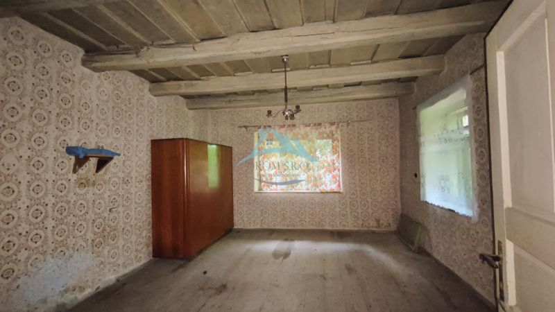 Alte Tapeten, Holzdecke, Regal und Schrank im Zimmer eines Einfamilienhauses.