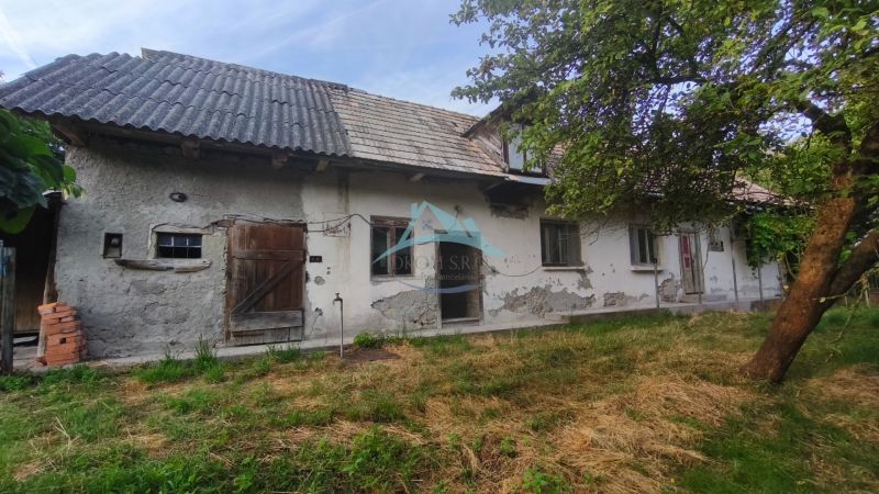 Ein Einfamilienhaus in Čelovce mit abgenutztem Putz, Holztüren und einem Garten.