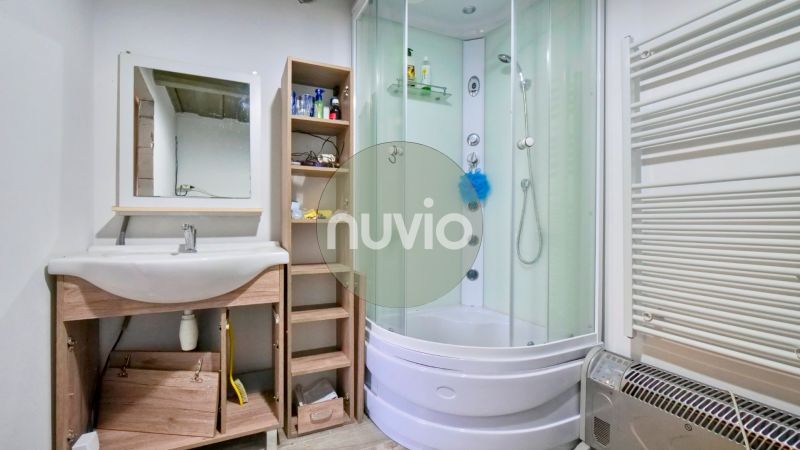 Ein Badezimmer in einem Einfamilienhaus mit einer Eckdusche und einem Waschbecken.