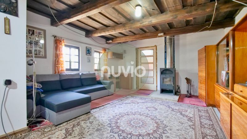 Wohnzimmer in einem Einfamilienhaus mit Holzbalkendecke, Sofa und Kachelofen.