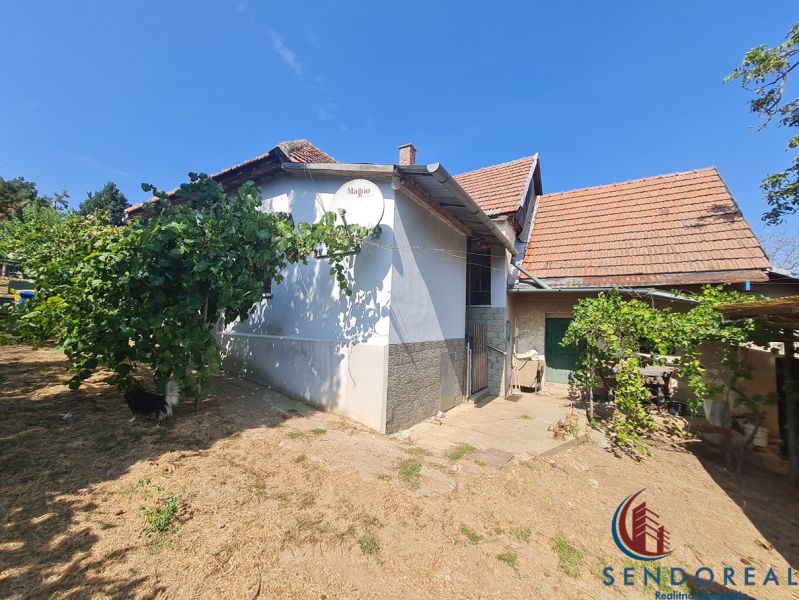 Ein Einfamilienhaus in Dolné Otrokovce mit weißem Putz und Ziegeln, grüne Pflanzen im Garten.