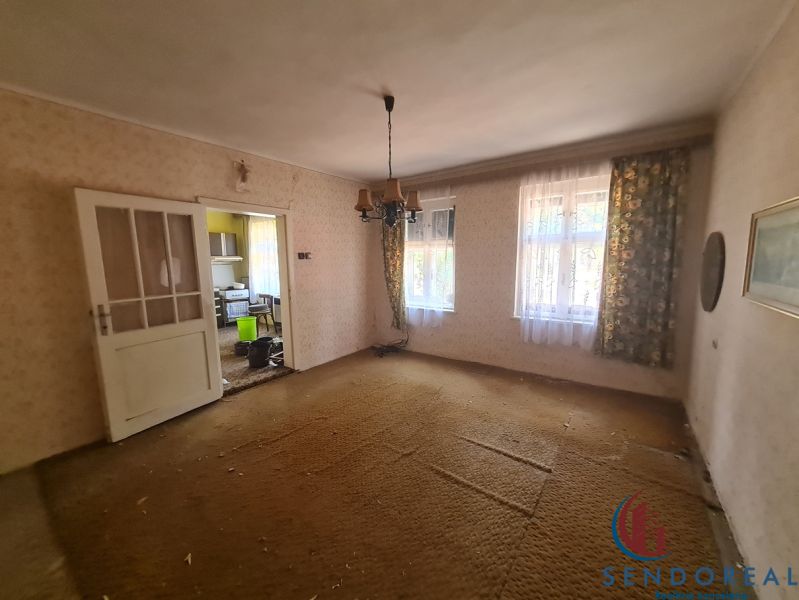 Wohnzimmer in einem Einfamilienhaus mit Teppichboden und antikem Kronleuchter.