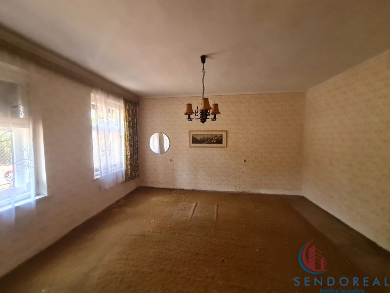Innenraum eines Einfamilienhauses mit Teppichboden, Licht und Vorhängen an den Fenstern.