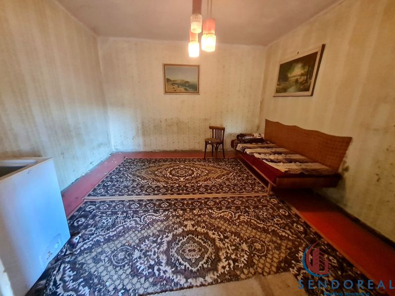 Ein Zimmer in einem Einfamilienhaus mit Teppich, Stuhl und Sofa.