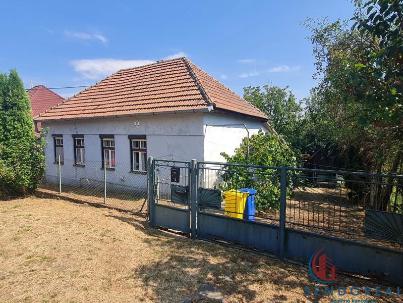 Ein Einfamilienhaus in Dolné Otrokovce mit einem Zaun und einem Garten auf einem sonnigen Grundstück.