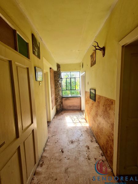 Der Flur in einem Einfamilienhaus mit einem Fenster am Ende und Dekorationen an den Wänden.