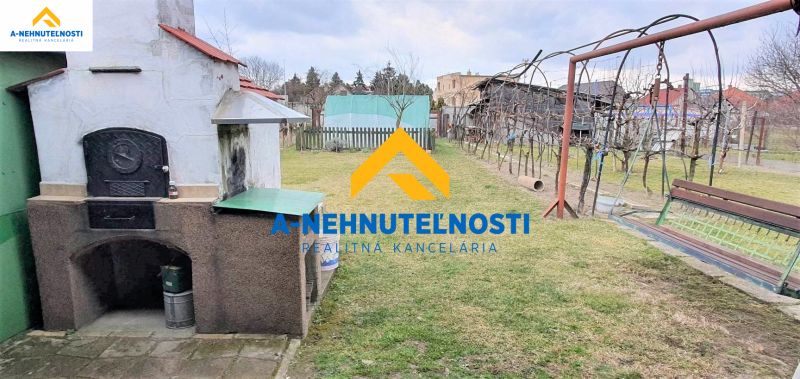 Der Hof des Einfamilienhauses in Veľký Meder mit einem Außenkamin und einem Pavillon auf dem Rasen.