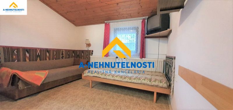 Ein Zimmer in einem Einfamilienhaus mit einem Sofa, einem Bett und einem Fernseher an der Wand.