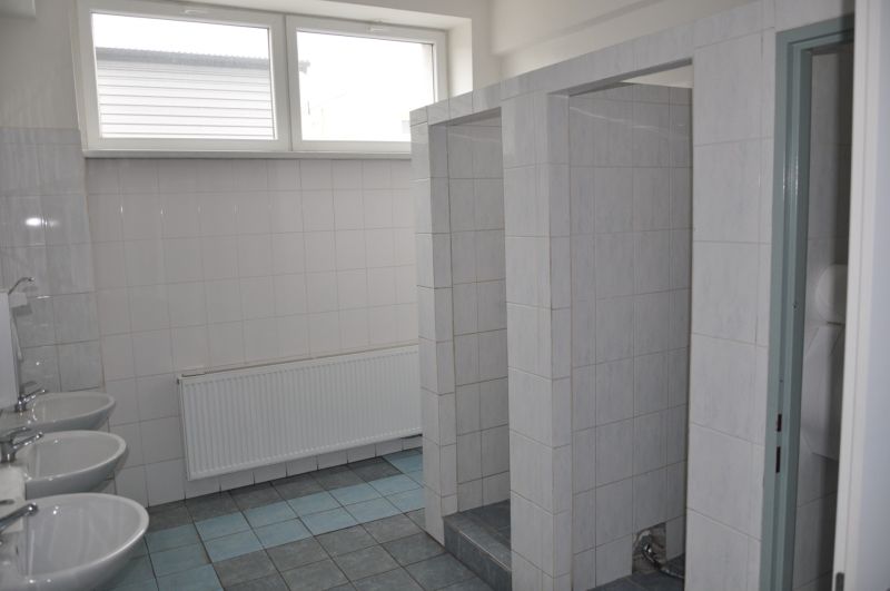 Badezimmer in Produktionsräumen mit gefliestem Boden und mehreren Waschbecken.