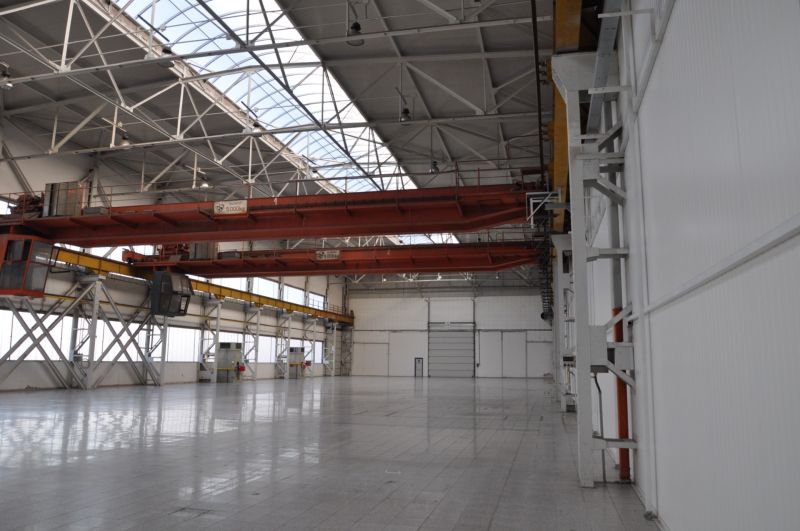 Industriehalle in Produktionsräumen mit zwei Kränen und verglastem Dach.
