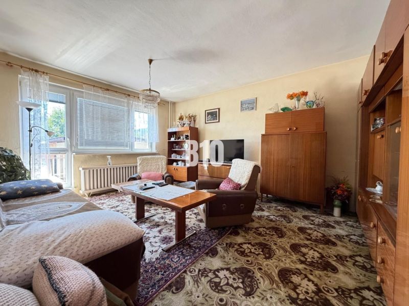 Wohnzimmer in einem Einfamilienhaus mit Holzmöbeln und dekorativem Teppich.
