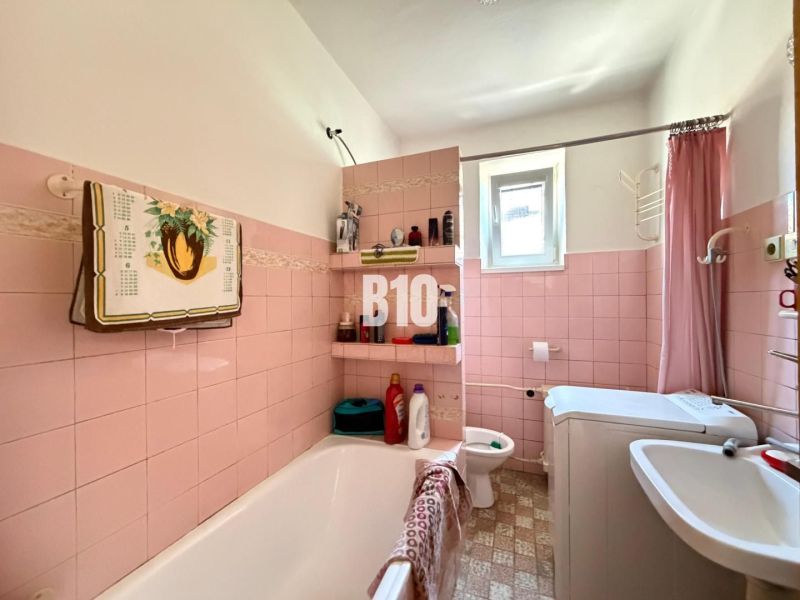 Ein Badezimmer in einem Einfamilienhaus mit rosa Fliesen und einer Badewanne.