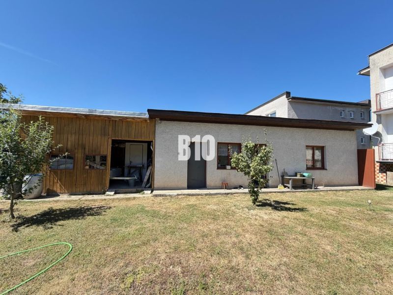 Ein Einfamilienhaus in Kláštor pod Znievom mit einem Holzvorbau und einem Rasen auf einem sonnigen Grundstück.