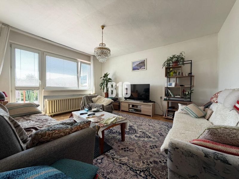 Wohnzimmer in einem Einfamilienhaus mit großen Fenstern, Holzboden und bequemen Sitzgelegenheiten.