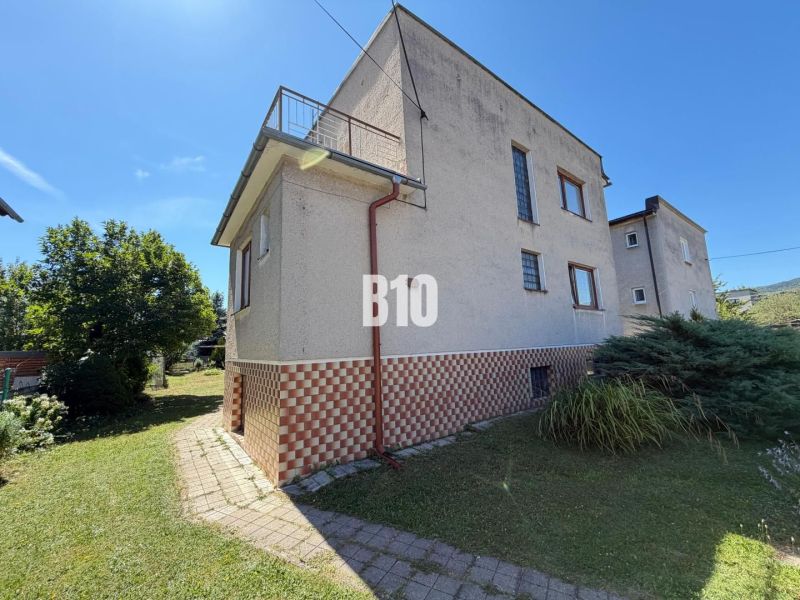 Ein Einfamilienhaus in Kláštor pod Znievom, Gras und Gehweg, Ziegelsockel.
