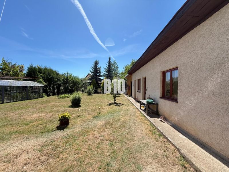 Ein Einfamilienhaus in Kláštor pod Znievom mit Garten und Gewächshaus an einem sonnigen Tag.
