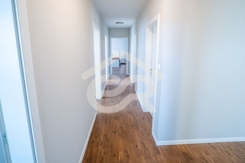 Ein Flur in einem Einfamilienhaus mit einem Boden in Holzoptik und weißen Wänden.