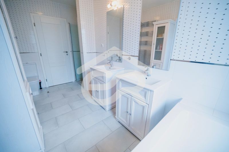 Ein Badezimmer mit zwei Waschbecken, einer Badewanne und Fliesen in einem Einfamilienhaus.