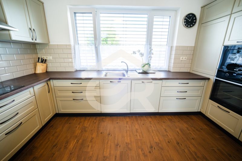 Eine Küche in einem Einfamilienhaus mit beigen Schränken und einem Boden in Holzoptik.