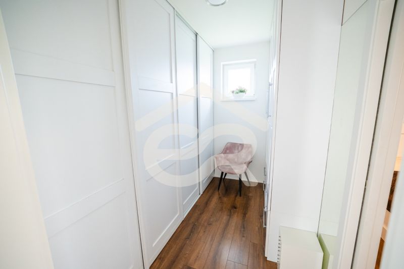 Ein enger Flur in einem Einfamilienhaus mit einem Holzboden und einem Fenster.