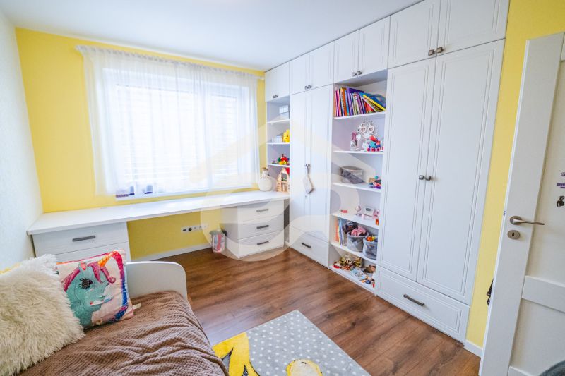 Kinderzimmer mit Bett, Regalschrank und Holzboden in einem Einfamilienhaus.