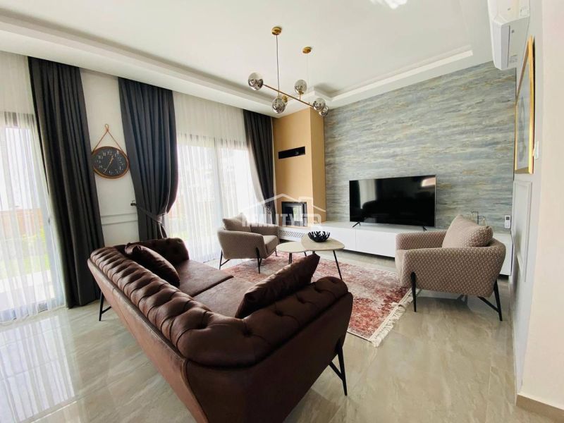 Wohnzimmer in einem Einfamilienhaus mit luxuriösem Sofa, Teppich und großem Fernseher.