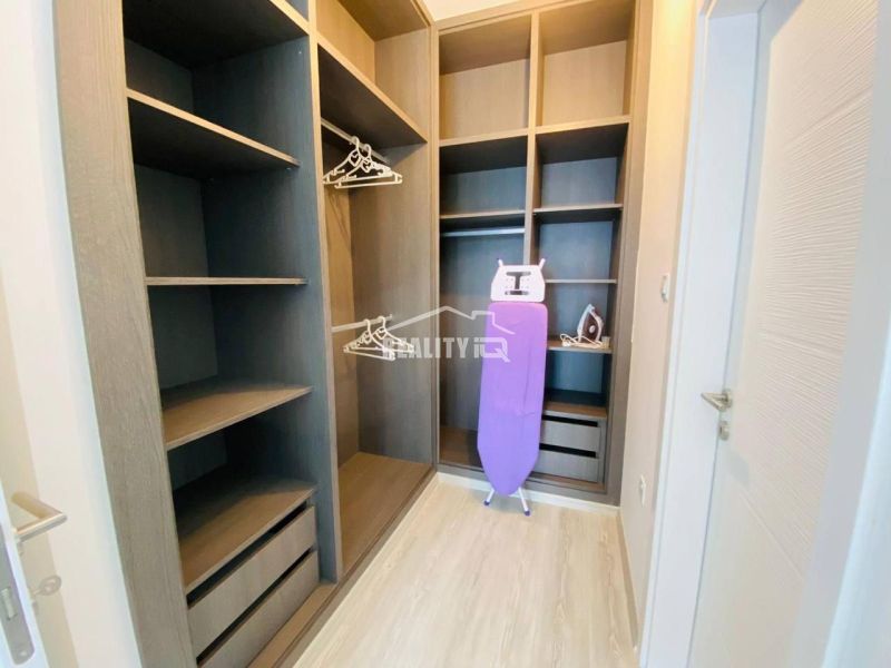 Ein Kleiderschrank im Einfamilienhaus mit Regalen, Kleiderbügeln und einem Bügelbrett.