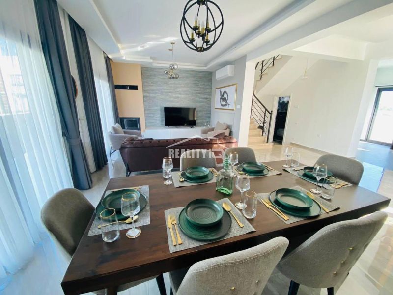 Esszimmer in einem Einfamilienhaus mit eleganter dunkler Ausstattung und sechs Stühlen.