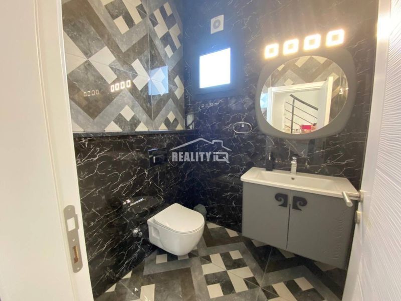 Ein Badezimmer in einem Einfamilienhaus mit dunkler Verkleidung und geometrischen Mustern an den Wänden.